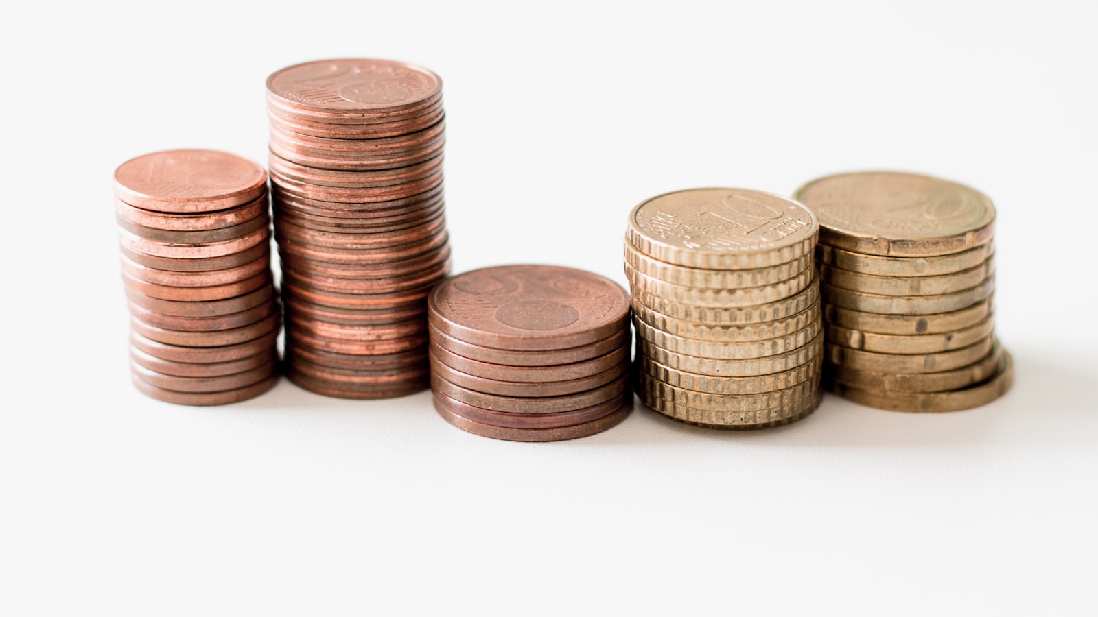 Stacked coins on a white surface, representing the choice between a Swiss bank deposit and investing through Maclear.